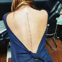 the back of a woman's neck with writing on her lower back and upper back