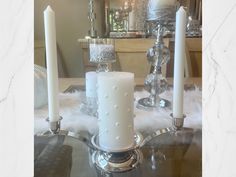 three candles are sitting on top of a glass table with white fur in the background