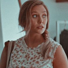 a woman in a floral top looking at the camera with an intense look on her face