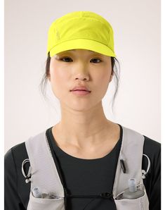 a woman wearing a yellow visor and grey overalls is looking at the camera