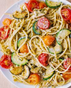 a white plate topped with pasta and veggies on top of a wooden table