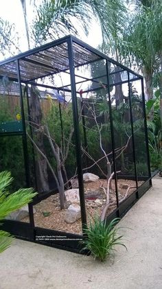 a small glass enclosure in the middle of a garden with rocks and plants inside it