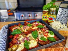 a pan filled with meat covered in sauces and vegetables on top of a wooden cutting board