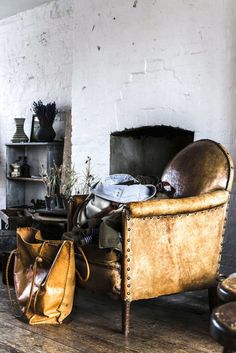 an old leather chair sitting on top of a wooden floor next to a fire place