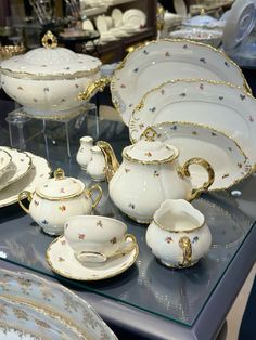 a table topped with lots of white and gold dishes