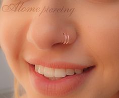 a close up of a person with a nose ring on their nose and the word home piercing written in gold