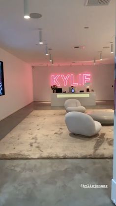 an empty room with white furniture and neon signs on the wall behind it that reads kylf