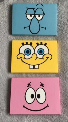 three cartoon faces painted on canvases in different colors