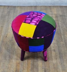 a multicolored stool sitting on top of a hard wood floor