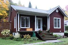 a small red house with steps leading to the front door and stairs up to the second floor