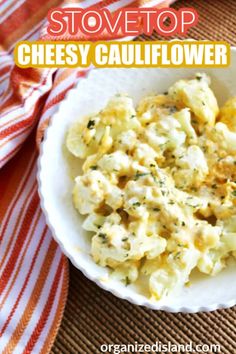 a white bowl filled with cheesy cauliflower on top of a table