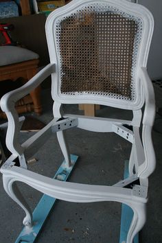 an old white rocking chair is being worked on