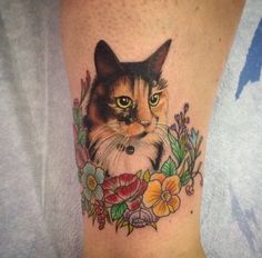 a close up of a cat with flowers on it's leg and the face of a cat