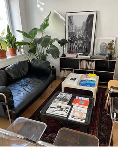 a living room with black leather couches and tables in front of a large window