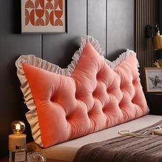 a pink bed with ruffled edges and an orange pillow on it's headboard