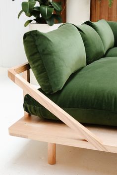 a green couch sitting on top of a wooden table next to a potted plant