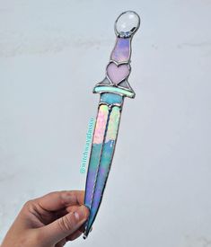 a hand holding a multicolored holographic knife with a heart on it