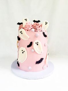 a pink halloween cake decorated with white icing and spooky bats