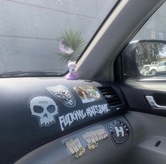 a car with stickers on the front window and skull decals on the passenger side mirror