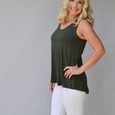 a woman standing with her hands on her hips wearing white pants and a green tank top