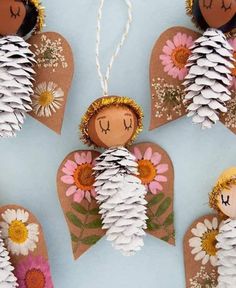 paper angel ornaments with pine cones and flowers on the top one is made out of cardboard