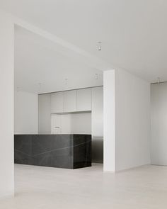 an empty room with white walls and marble counter top in the center, as well as cabinets