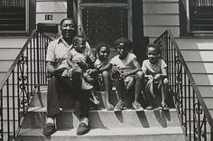 an old black and white photo of four children sitting on the front steps of a house