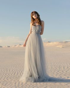 a woman standing in the sand wearing a dress