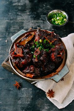 a pot filled with meat and vegetables sitting on top of a table next to other dishes