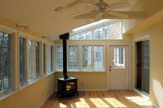 the sun shines through the windows in this empty room with a stove and ceiling fan