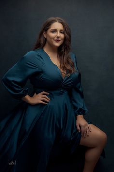 a woman in a blue dress is posing for a studio photo with her legs crossed