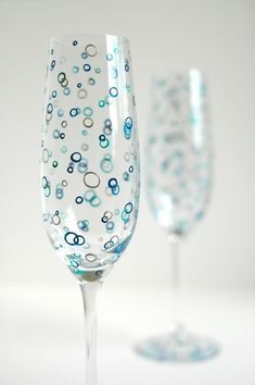 two wine glasses sitting next to each other on top of a white table with blue dots