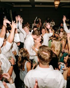 a group of people standing around each other with their hands in the air and one person holding up his cell phone