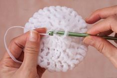 two hands holding yarn and knitting needles over a ball of yarn with another person's hand