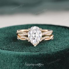 an oval diamond ring sits on top of a green velvet box, with the band around it's edge