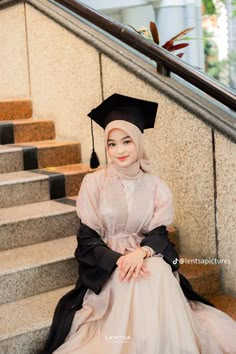 a woman in a graduation gown sitting on some stairs