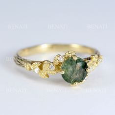 a gold ring with a green stone surrounded by leaves