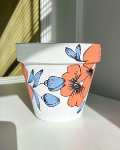 a white bowl with orange and blue flowers painted on the side sitting on a table