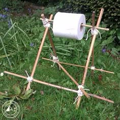 a roll of toilet paper sitting on top of a wooden easel in the grass