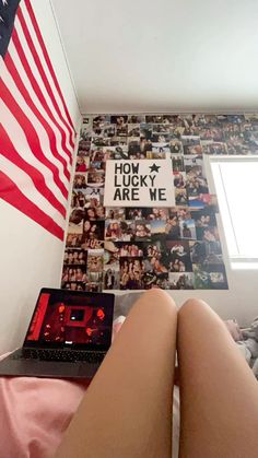 a laptop computer sitting on top of a bed next to a wall covered in pictures