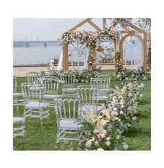 an outdoor ceremony setup with chairs and flowers on the grass, overlooking the water's edge