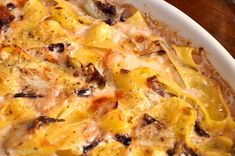 a casserole dish with cheese and mushrooms in it on a wooden table top