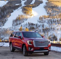 a red truck parked on top of a snow covered slope