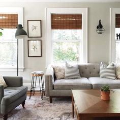 a living room with two couches and a coffee table in front of three windows