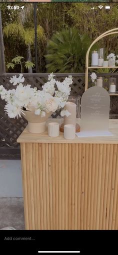 a wooden table topped with vases filled with flowers next to a white and black sign