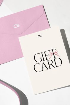 a pink and white gift card sitting on top of a table next to an envelope