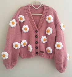 a pink cardigan with white flowers on the front and brown buttons in the back