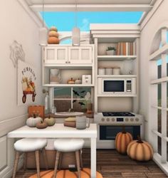 the kitchen is decorated in white and has pumpkins on the floor, as well as a table with two stools