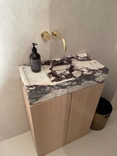 a bathroom vanity with marble counter top and gold faucet