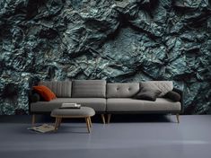 a couch sitting in front of a wall covered in green and black rock formation paper